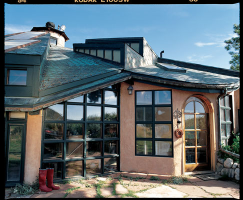 Massive beams made of beetle-kill pine radiate from a silo constructed from recycled bricks, which acts as the home’s main structural post and also as a chimney and vent for solar heat. Susan found the 1930s stove through the classifieds.